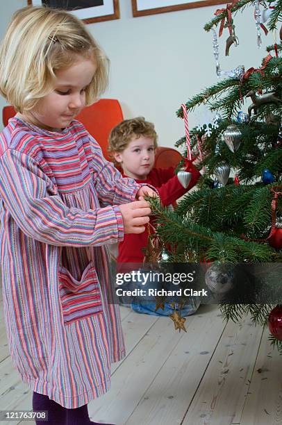 boy and girl hanging christmas decorations - clark bros stock pictures, royalty-free photos & images