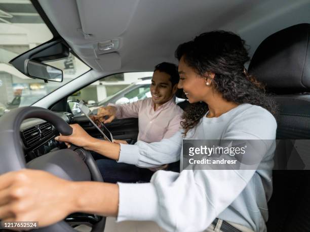 woman talking to a salesman at the dealership before taking a car for a test drive - car dealership test drive stock pictures, royalty-free photos & images