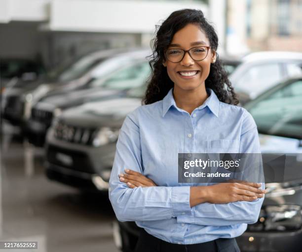 portrait of a happy saleswoman working at a car dealership - saleswoman stock pictures, royalty-free photos & images
