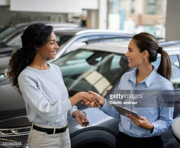 glückliche frau kauft ein auto und schließt den deal mit einem handschlag - customer service documents stock-fotos und bilder
