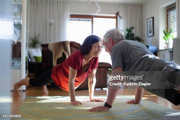 senior couple exercising at home - pandemic illness stock pictures, royalty-free photos & images