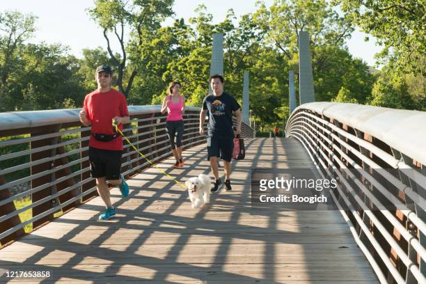 people walking across pedestrian bridge in buffalo bayou park in houston texas - houston people stock pictures, royalty-free photos & images