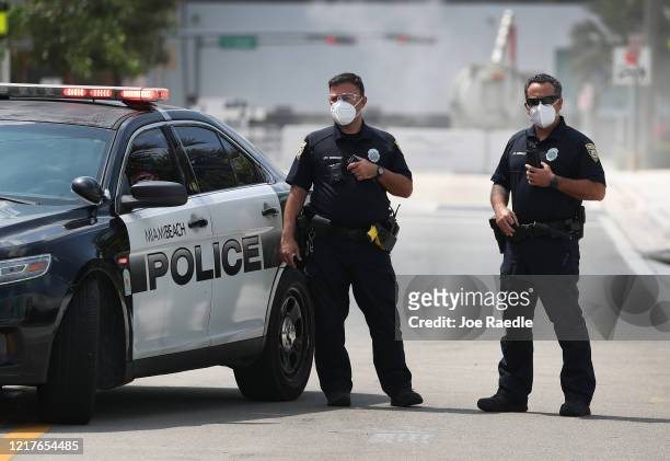 Miami Beach police officers wear protective masks as Florida Gov. Ron DeSantis along with other officials and politicians speak during a press...