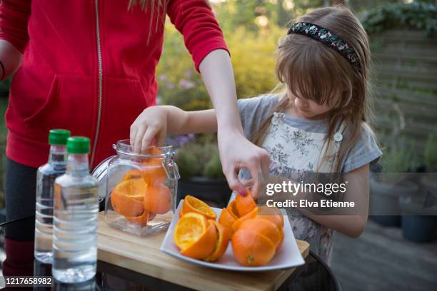 two children making use of leftover orange peels to make a zero waste cleaning solution with white vinegar - white vinegar stock pictures, royalty-free photos & images