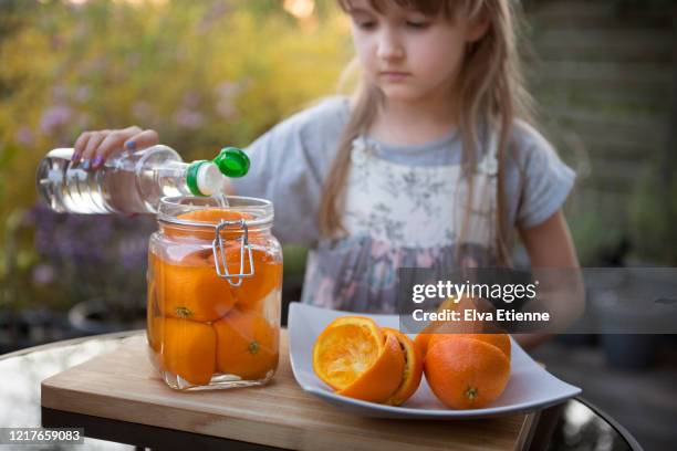 child making use of leftover orange peels to make a zero waste cleaning solution with white vinegar - white vinegar stock pictures, royalty-free photos & images