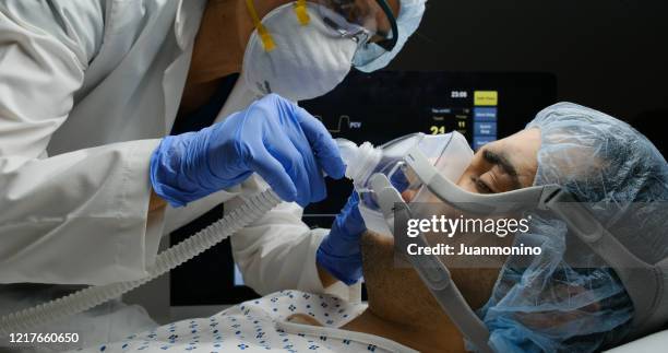 doctora femenina que revisa a la paciente infectada de covid-19 mientras está conectada a un respirador - ventilador equipo respiratorio fotografías e imágenes de stock