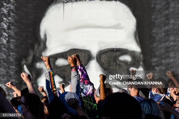 People raise their hands as they protest at the makeshift memorial in honour of George Floyd, on June 4, 2020 in Minneapolis, Minnesota. - On May 25...