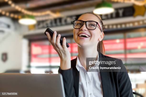 young businesswoman using the voice recognition of the phone - dictaphone stock pictures, royalty-free photos & images