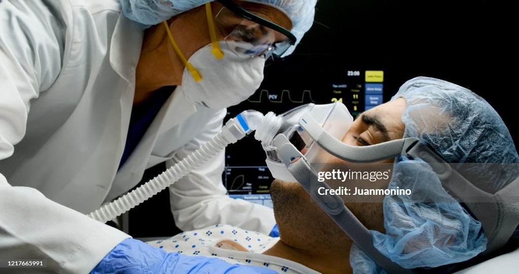 Female doctor checking on Covid-19 infected patient while connected to a ventilator