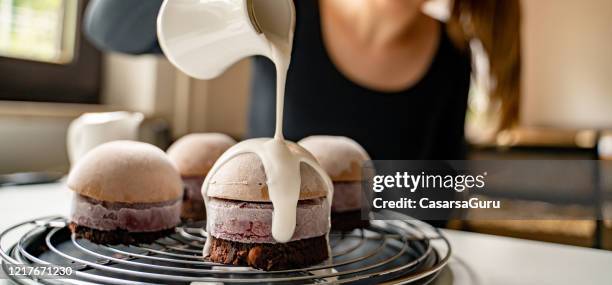 frau pouring white icing auf hausgemachte dessert auf rack - stock foto - soirée mousse stock-fotos und bilder