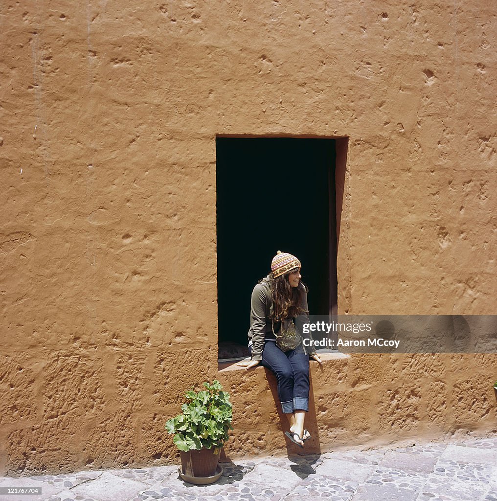 Girl (20-25 years) sitting on window ledge, South America