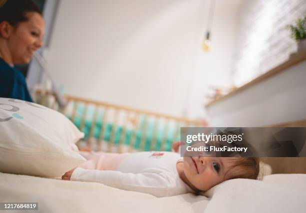 lovely mother preparing her baby daughter for sleep - mother and daughter making the bed stock pictures, royalty-free photos & images