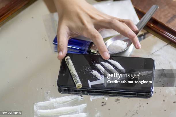 young man hand touch a syringe and drug overdose,the concept of crime and drug addiction. - snorted stock pictures, royalty-free photos & images