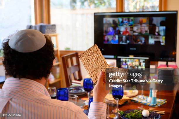 Minneapolis, MN April 8: Bruce Manning held up matzo, which he just broke in half as part of Passover seder ritual, as he took part in a virtual...