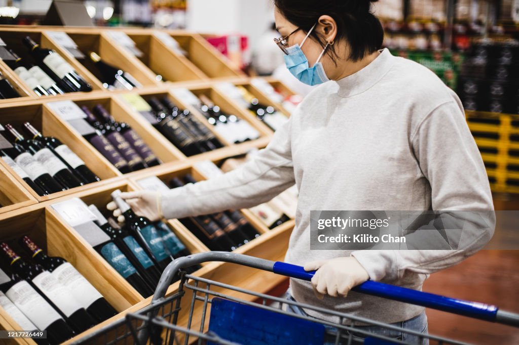 Asian female buying some wine at a supermarket