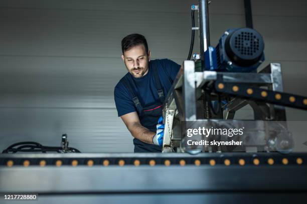 jonge arbeider die aan een productielijnmachine in een fabriek werkt. - werktuigbouwkunde stockfoto's en -beelden