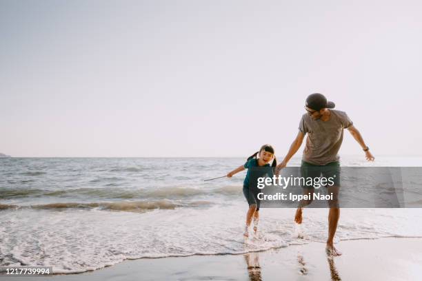 father and child running on beach - day 6 foto e immagini stock