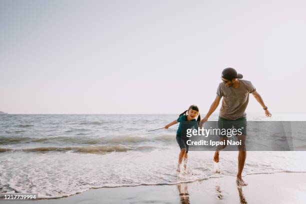 father and child running on beach - asian on beach bildbanksfoton och bilder