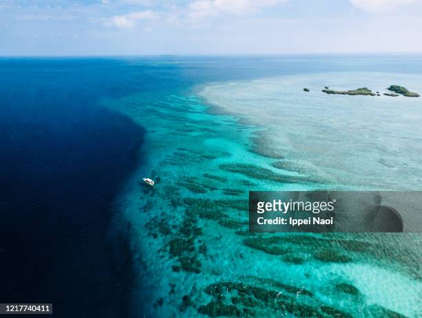 aerial view of coral reef with blue tropical water and boat, okinawa, japan - insel iriomote stock-fotos und bilder