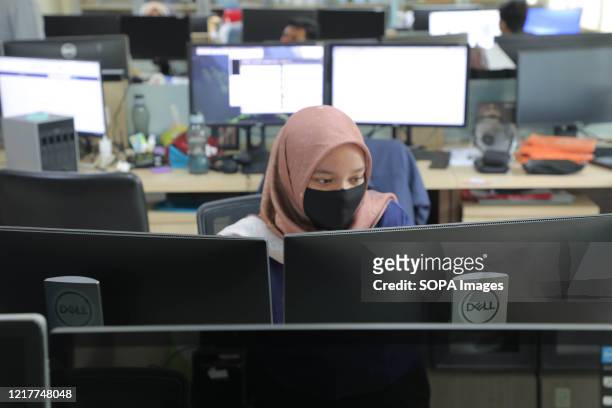 Civil servant working while wearing a face mask as a preventive measure in a government office during the transition period. Jakarta and its...