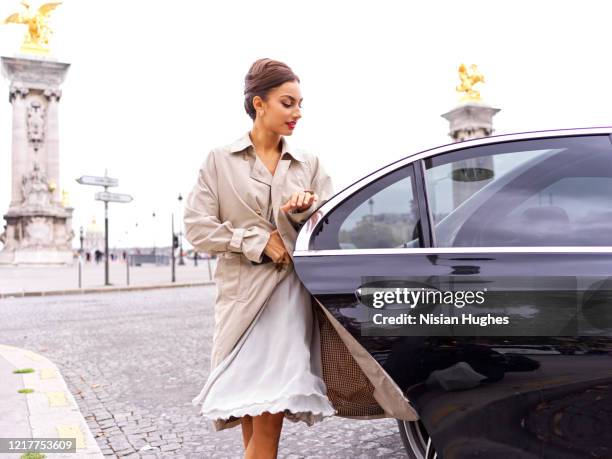 stylish young women getting out of back of car, daytime - auto aussteigen stock-fotos und bilder