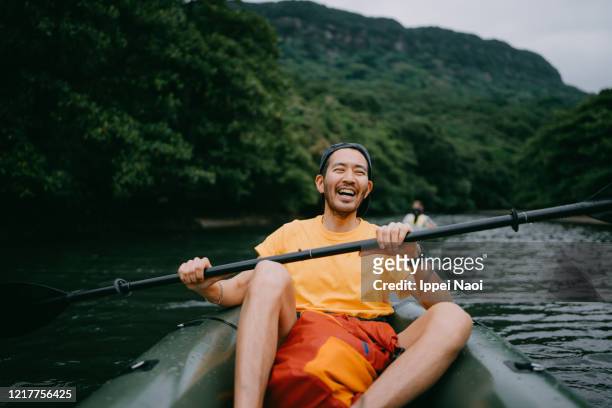 man paddling kayak in mangrove river and laughing, iriomote, japan - atividades de fins de semana imagens e fotografias de stock