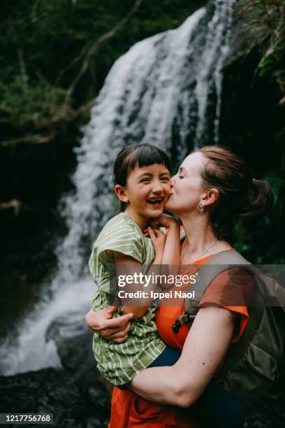 mother holding little girl in front of waterfall - eurasian ethnicity stock pictures, royalty-free photos & images