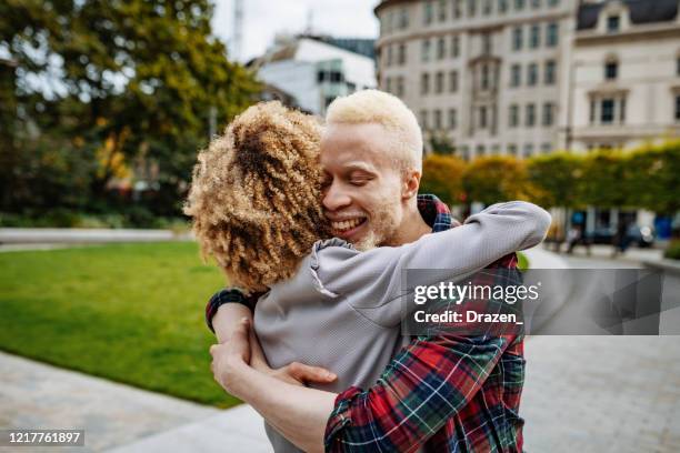 albino african man hugging his curly girlfriend - white skin stock pictures, royalty-free photos & images