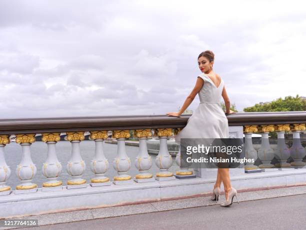stylish woman leaning on railing of bridge in paris france looking out over the seine river, daytime - white dress back stock pictures, royalty-free photos & images