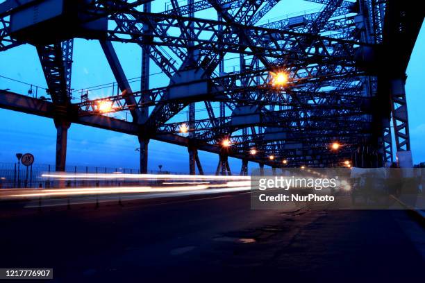 Commuters ride their bicycles and two wheeler past the landmark Howrah Bridge over Ganga River after the government eased a nationwide lockdown...