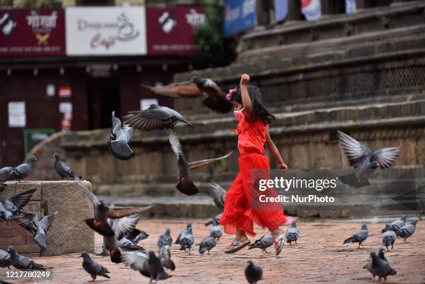 Little girl along with the face mask playing with Pigeons in the empty Patan Durbar square UNESCO world heritage sites during ongoing nationwide...