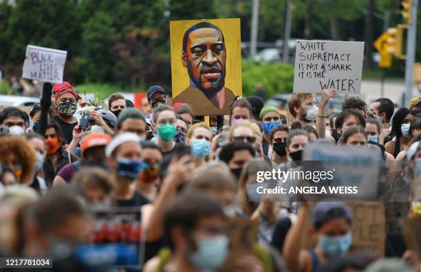 Protester holds up a portrait of George Floyd during a "Black Lives Matter" demonstration in front of the Brooklyn Library and Grand Army Plaza on...