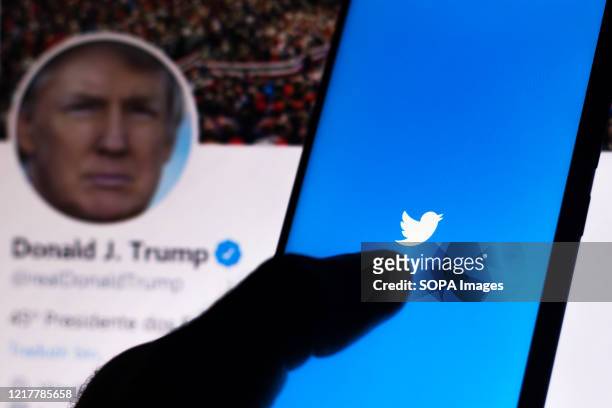 In this photo illustration the Twitter logo seen displayed on a smartphone with the official page of the President of the United States, Donald...