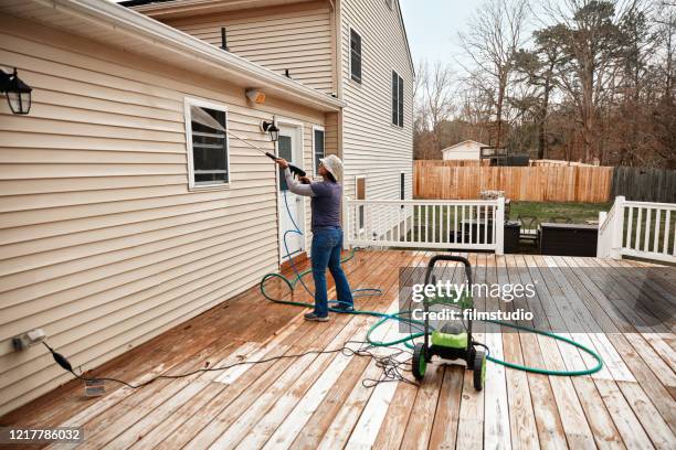 frau reinigung holzterrasse mit einem hochwasserdruckreiniger - high pressure cleaning stock-fotos und bilder