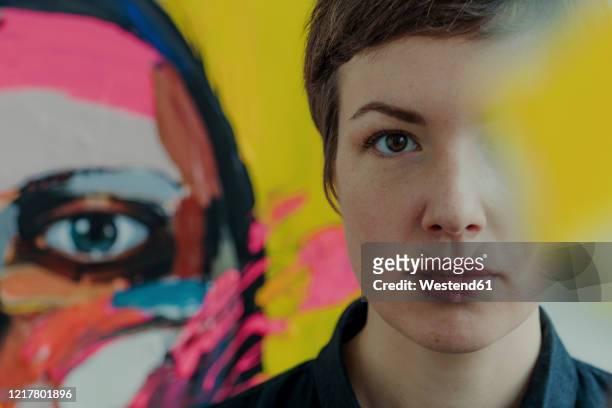 portrait of a female painter with painting in background - creative occupation stock-fotos und bilder