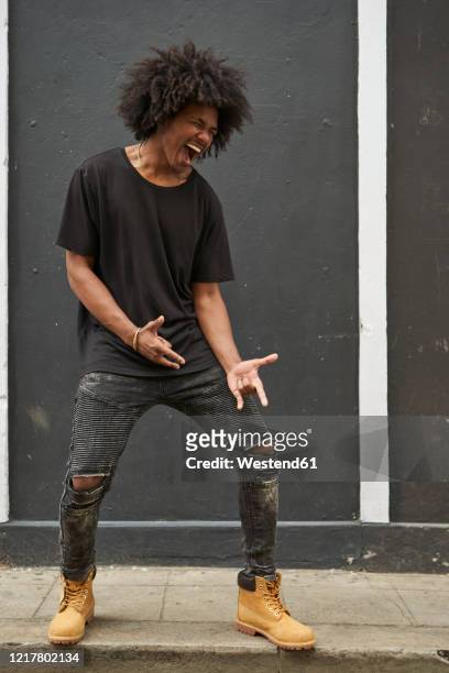 young black man with afro singing and dancing in front of grey wall - black boot stock pictures, royalty-free photos & images