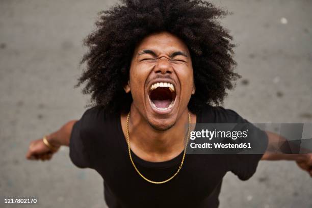 portrait of screaming young man with afro - boca aberta - fotografias e filmes do acervo