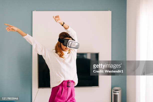 happy young woman wearing vr glasses at home - fernseher tanzen home stock-fotos und bilder