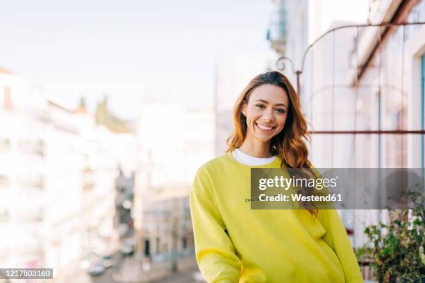 portrait of happy young woman standing on balcony - sweatshirt fotografías e imágenes de stock