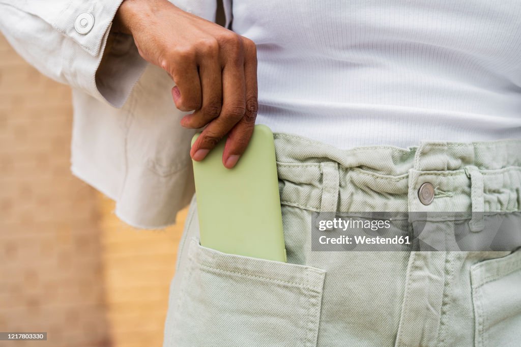 Close-up of woman putting smartphone into her pocket