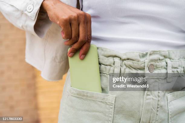 close-up of woman putting smartphone into her pocket - hands in pockets foto e immagini stock