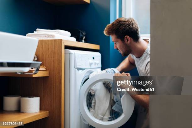 young man doing the laundry at home - colada fotografías e imágenes de stock