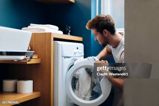 young man doing the laundry at home - washing machine 個照片及圖片檔