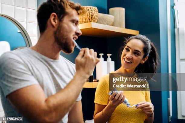 young couple brushing their teeth in bathroom at home - brushing teeth stock pictures, royalty-free photos & images