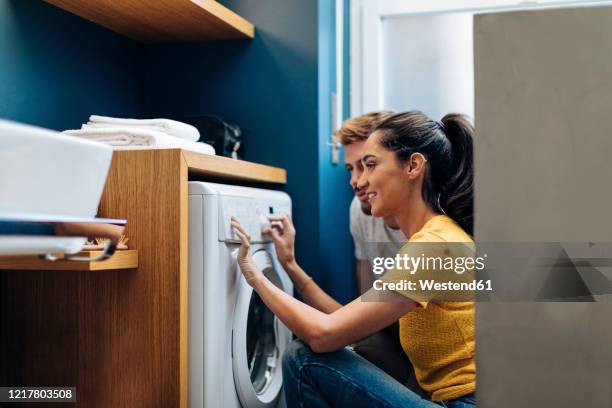 young couple doing the laundry at home - home appliances ストックフォトと画像