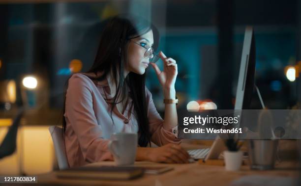 young woman with glasses working at desk in office - solo una donna giovane foto e immagini stock