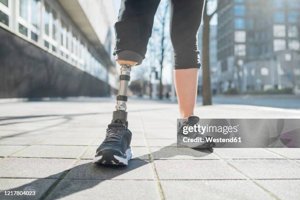 close-up of legs of sporty woman with leg prosthesis in the city - prosthetics stock pictures, royalty-free photos & images