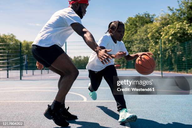 father and son playing basketball on basketball court - dribbling stock pictures, royalty-free photos & images