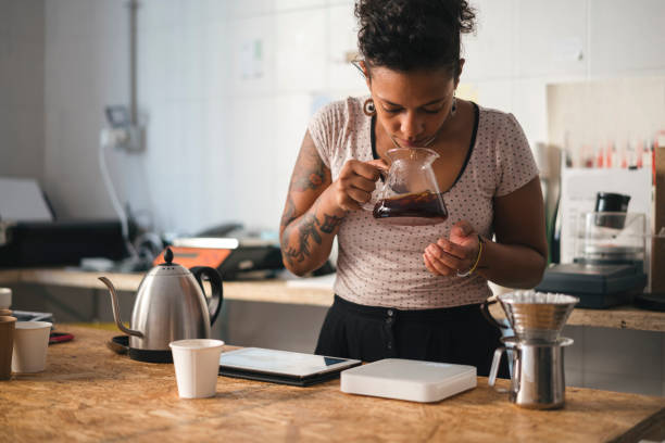 woman working in a coffee roastery smelling at coffee - professional coffee roaster stock pictures, royalty-free photos & images