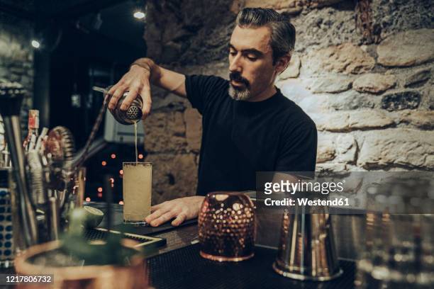 bartender pouring cocktail in a glass - bartender stock pictures, royalty-free photos & images